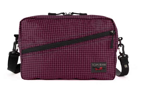 A Packing Cube Shoulder Bag in Acai (dark purple with white grid) 200 Halcyon with a shoulder strap attached